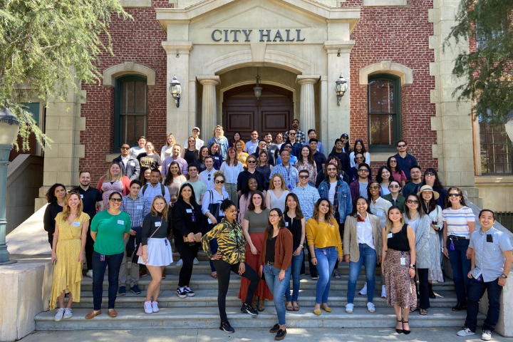 A photograph of 50 new employees standing on the steps to Universal's back lot set of City Hall.